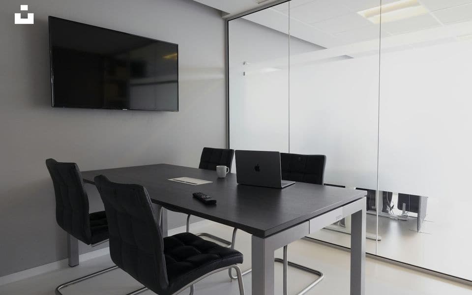 Modern meeting room with conference table, chairs, and large presentation display