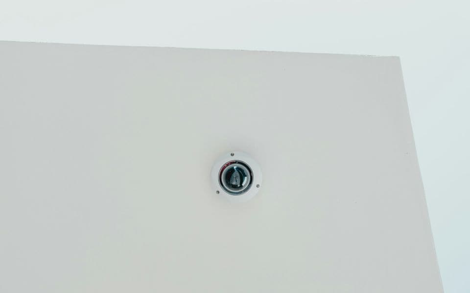 A ceiling-mounted dome security camera in a commercial building lobby