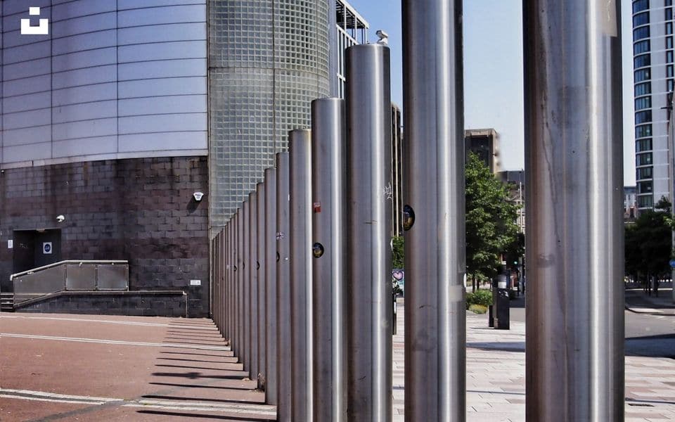 Row of cylindrical stainless steel perimeter security bollards along pavement