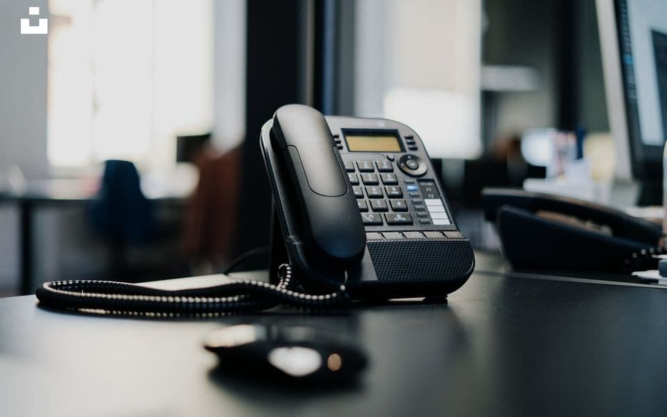Commercial IP desk phone with handset and numeric keypad on office desk